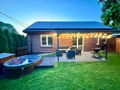 a small house with a hot tub in the yard at Domek nad Jeziorem Siamoszyce in Siamoszyce