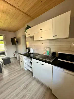 a kitchen with white cabinets and a black counter top at Domek nad Jeziorem Siamoszyce in Siamoszyce
