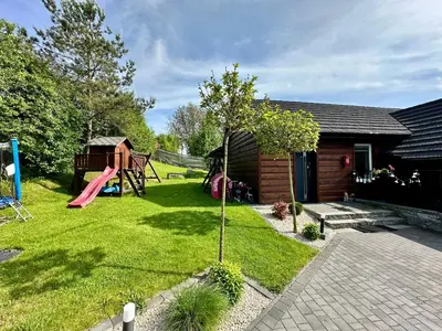 a small yard with a playground and a house at Domek nad Jeziorem Siamoszyce in Siamoszyce