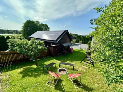 a yard with chairs and a table and a house at Domek nad Jeziorem Siamoszyce in Siamoszyce