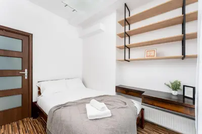 a bedroom with a white bed and a wooden desk at Komorowskiego Riverside Apartment by BookingHost in Kraków