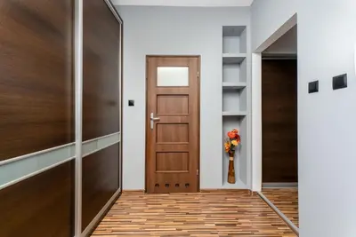 a hallway with a wooden door and a vase of flowers at Komorowskiego Riverside Apartment by BookingHost in Kraków