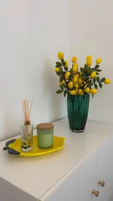 a table with a plate and a vase with yellow flowers at Golden Age Apartment Cracow in Kraków