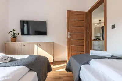 a bedroom with two beds and a television on the wall at Domek z Widokiem in Zator