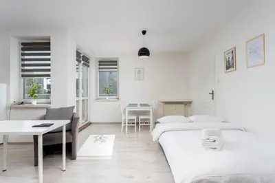 a white bedroom with two beds and a table at Osiedle Oświecenia Comfort Apartment by BookingHost in Kraków