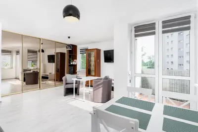 a white apartment with a dining room and living room at Osiedle Oświecenia Comfort Apartment by BookingHost in Kraków