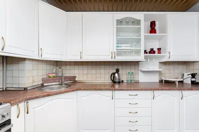 a white kitchen with white cabinets and a sink at Osiedle Oświecenia Comfort Apartment by BookingHost in Kraków
