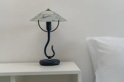 a lamp sitting on a table next to a bed at Osiedle Oświecenia Comfort Apartment by BookingHost in Kraków