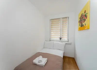 a small bedroom with a bed and a window at Osiedle Piastów Comfort Apartment by BookingHost in Kraków
