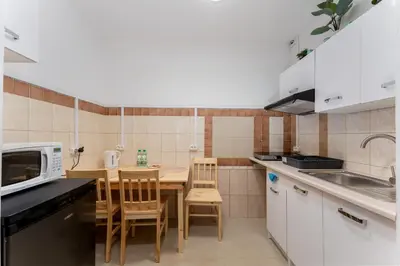 a kitchen with a table and chairs and a microwave at Osiedle Piastów Comfort Apartment by BookingHost in Kraków