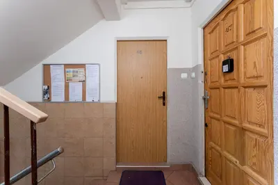 a hallway with a wooden door and a staircase at Osiedle Piastów Comfort Apartment by BookingHost in Kraków