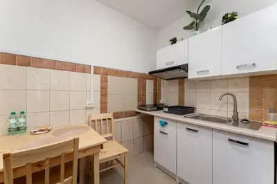 a kitchen with white cabinets and a wooden table at Osiedle Piastów Comfort Apartment by BookingHost in Kraków