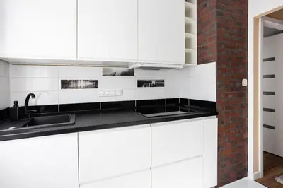 a kitchen with white cabinets and a brick wall at Beautiful Apartment Avia with balcony in Cracow city in Kraków