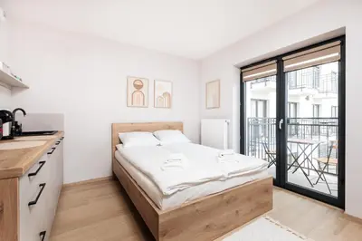 a white bedroom with a bed and a balcony at City of the Kings - Corner 12 in Kraków