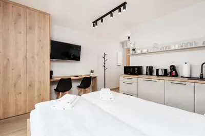 a white kitchen with two chairs and a large bed at City of the Kings - Corner 12 in Kraków