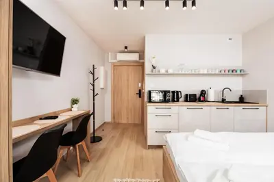 a bedroom with a bed and a desk and a kitchen at City of the Kings - Corner 12 in Kraków