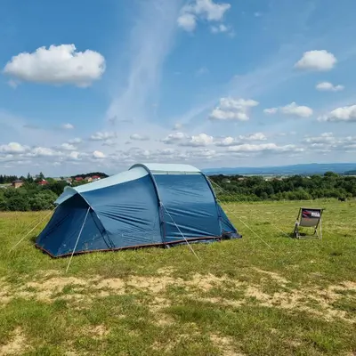 a blue tent in a field with a chair at Uszate Ranczo in Rybna