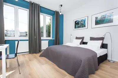 a bedroom with a bed and a desk and windows at Krakow B&B in Kraków