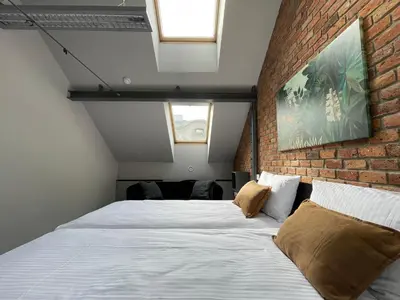 a bedroom with a large bed with a brick wall at Atelier Stare Miasto in Chrzanów