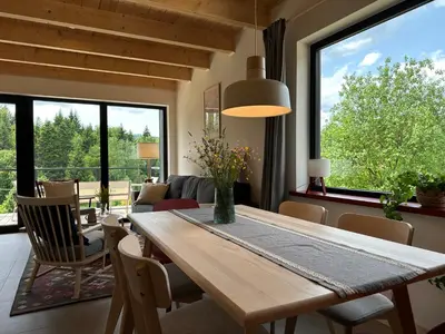 a dining room with a table and chairs and windows at BeskiDom in Zawoja