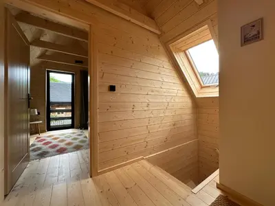 an attic room with wooden walls and a window at BeskiDom in Zawoja