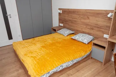 a bedroom with a bed with an orange blanket at Apartament Bonarka in Kraków