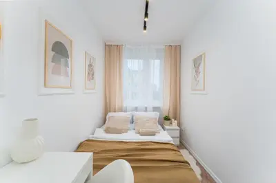 a small white room with a bed and a window at Osiedle Kazimierzowskie in Kraków