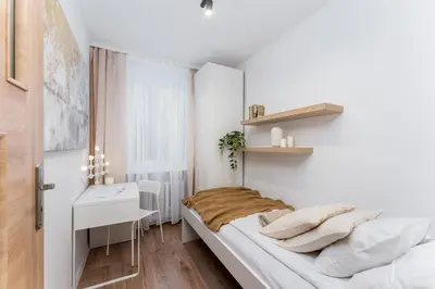 a small white bedroom with a bed and a desk at Osiedle Kazimierzowskie in Kraków