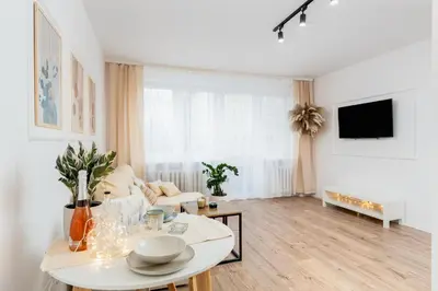 a white living room with a table and a couch at Osiedle Kazimierzowskie in Kraków