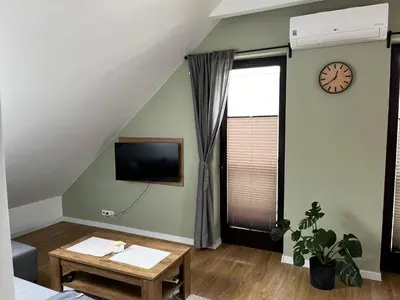 a living room with a table and a clock on the wall at Apartamenty Rubikon in Kraków