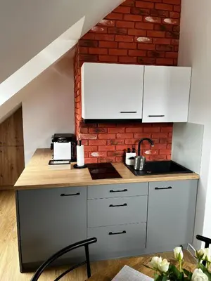 a kitchen with white cabinets and a brick wall at Apartamenty Rubikon in Kraków