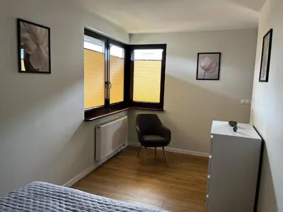 a bedroom with a bed and a chair and windows at Apartamenty Rubikon in Kraków