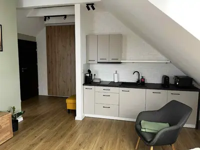 a kitchen with white cabinets and a chair in a room at Apartamenty Rubikon in Kraków