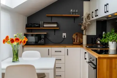 a kitchen with white cabinets and a black wall at Malila Premium Apartments Cracow Prażmowskiego 46 in Kraków