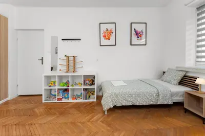 a white bedroom with a bed and a book shelf at Zabłocie Comfort House with parking and garden in Kraków