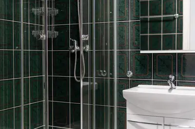 a green tiled bathroom with a toilet and a shower at Zabłocie Comfort House with parking and garden in Kraków