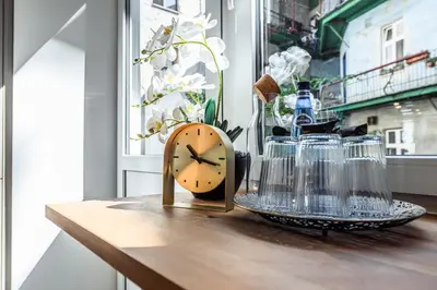 a clock sitting on top of a table with glasses at Golden Apartment by Cracovia Prime in Kraków