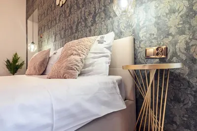 a bedroom with a bed and a wall with wallpaper at Golden Apartment by Cracovia Prime in Kraków