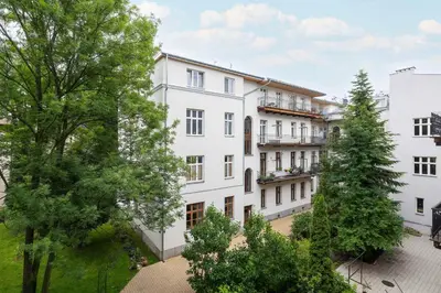 an apartment building with trees in the foreground at Charming Apartments with Desk in Downtown Cracow by Noclegi Renters in Kraków