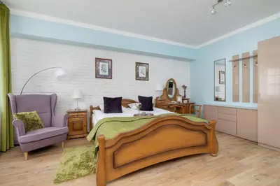 a bedroom with a large bed and a purple chair at Starowiślna Cozy Studio in Downtown Cracow by Noclegi Renters in Kraków