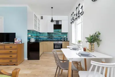 a kitchen and dining room with a white table and chairs at Starowiślna Cozy Studio in Downtown Cracow by Noclegi Renters in Kraków