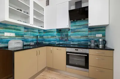 a kitchen with white cabinets and blue tiles on the wall at Starowiślna Cozy Studio in Downtown Cracow by Noclegi Renters in Kraków