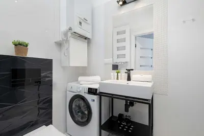 a white bathroom with a sink and a washing machine at Starowiślna Cozy Studio in Downtown Cracow by Noclegi Renters in Kraków