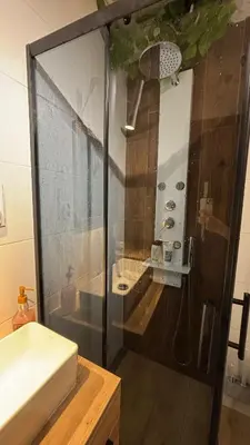a bathroom with a shower with a sink and a mirror at Stradom House Apartment in Kraków