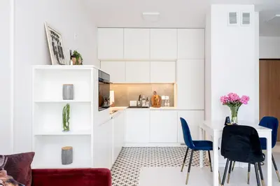 a kitchen with white cabinets and blue chairs at Malila Premium Apartments Cracow Tauron Arena Lema 15E in Kraków