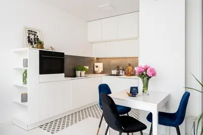 a white kitchen with blue chairs and a table at Malila Premium Apartments Cracow Tauron Arena Lema 15E in Kraków