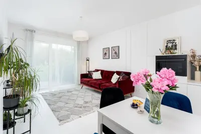 a living room with a red couch and pink flowers at Malila Premium Apartments Cracow Tauron Arena Lema 15E in Kraków