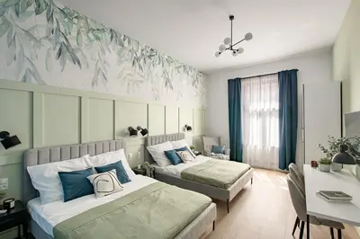 a bedroom with two beds with blue and green leaves on the wall at Kaleidoscope Apartment by Tyzenhauz in Kraków