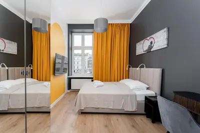 two beds in a room with yellow curtains at Old Market View Premium Standard with AC in Kraków