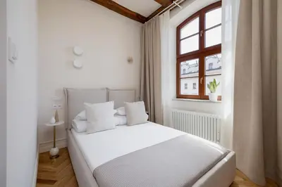a white bedroom with a white bed and a window at Modern apartment in the heart of the Old Town in Kraków